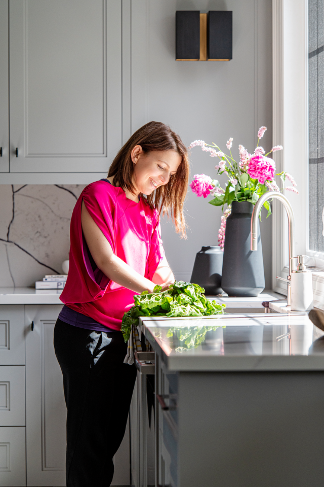 A woman cutting vegetables in a monochromatic kitchen